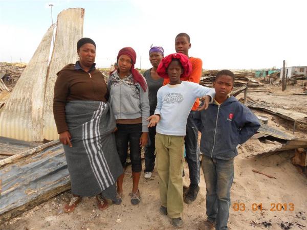 Ntombi and her family stand on their ruined house. Photo by Faizel Slamang.