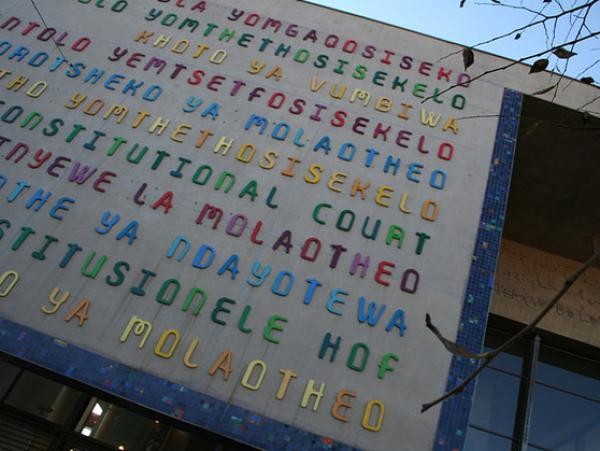 Photo of a wall with Constitutional Court written in various languages and colours