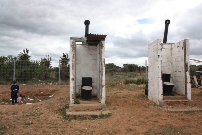 Photo of two open toilets in a field