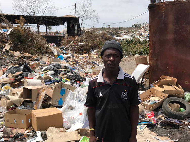 Photo of man standing next to rubbish dump