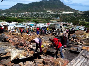 Photo of people cleaning up after fire in Imizamo Yethu.