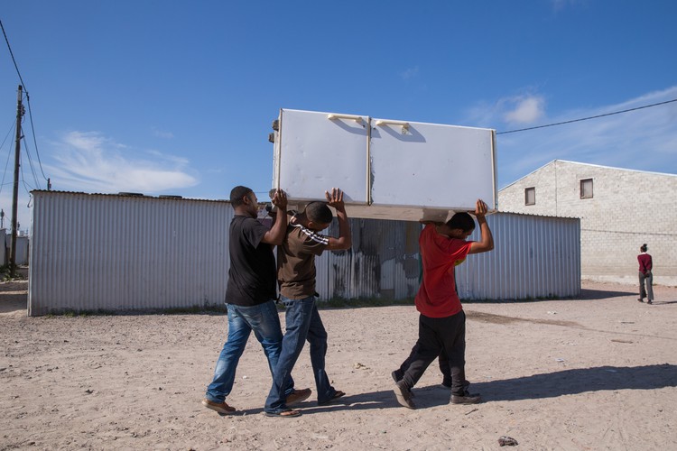 Photo of people carrying corrugated iron sheets