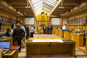 Photo of parliamentary committee room with people standing around