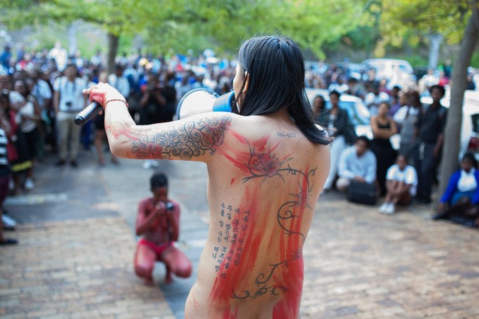 Photo of naked person addressing crowd 