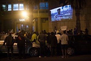 Photo of protest with video showing in background