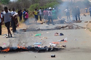 Photo of debris burning on road, with protesters