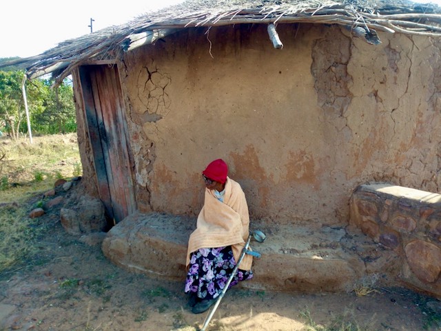 Photo of a woman in front of a dilapidated house