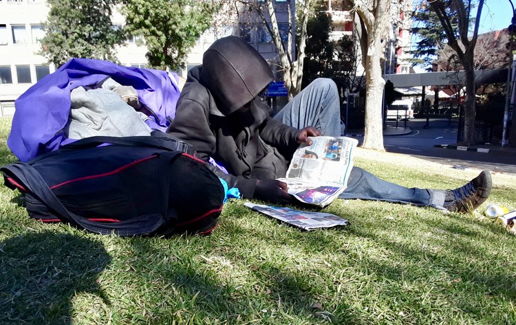 Photo of a hooded man reading a newspaper