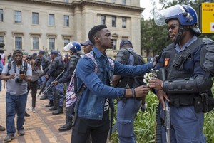 Photo of student protester handing flowers to police officer.