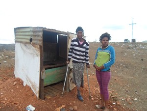 Photo of disabled woman and her friend in front of pit toilet