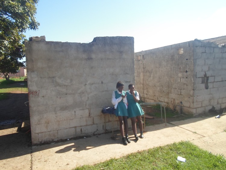 Photo of learners in front of dilapidated building