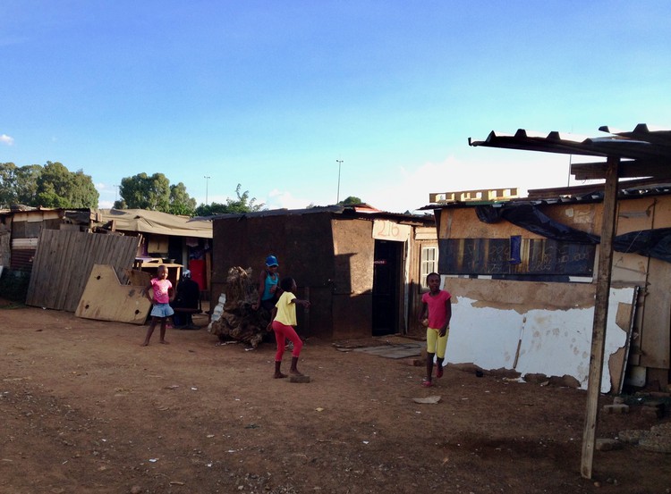 Photo of some kids and behind them shacks