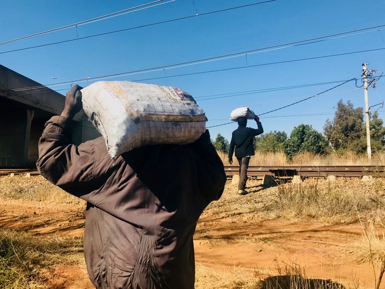 Photo of two men carrying sacks on their shoulders