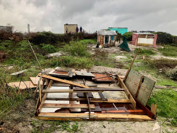 Photo of flattened shacks and a stormy sky