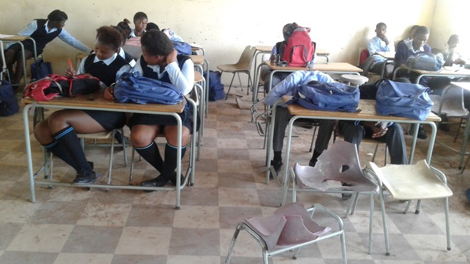 Picture of students in class with broken chairs