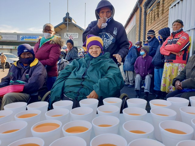 Seventy-one-year-old Elizabeth Jooste (centre) is one of hundreds of people who receive a hot meal and a food parcel every Thursday outside the Atlantis Pharmacy. Photos: Mary-Anne Gontsana