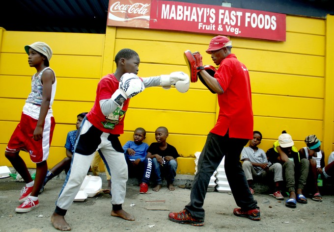Photo of a boy boxing with his coach.