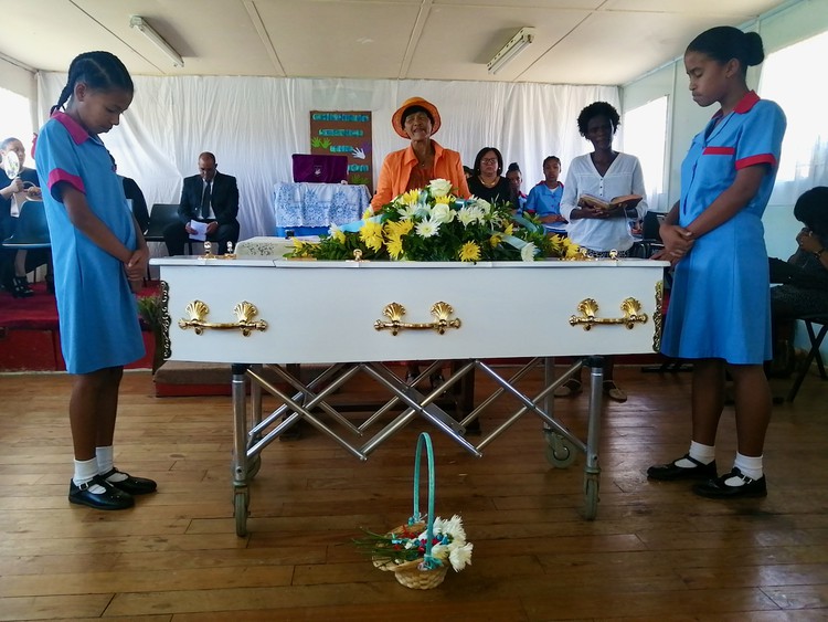 Photo of a coffin and mourners