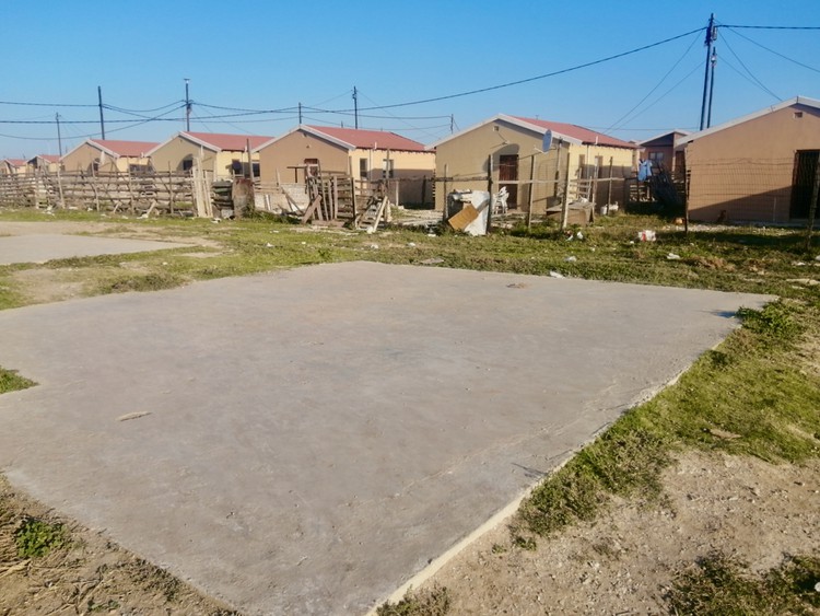 Photo of concrete slab and RDP houses behind it