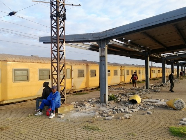 Photo of a man waiting on a dilapidated train station platform