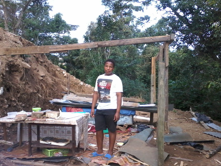 Photo of man in front of his demolished shack