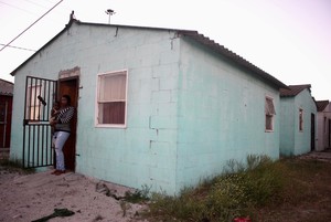 Photo of a woman and child outside a small house