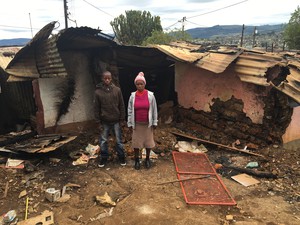Photo of two people in front of burned house