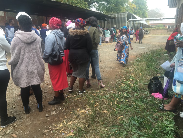 Photo of beneficiaries standing in a long line.