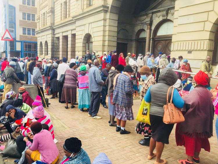 Photo of beneficiaries standing in snaking queues outside the post office