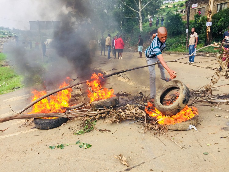 Photo of man throwing tyre onto fire