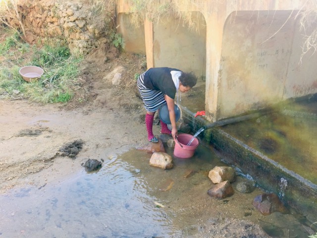 Photo of a woman with a bucket collecting water