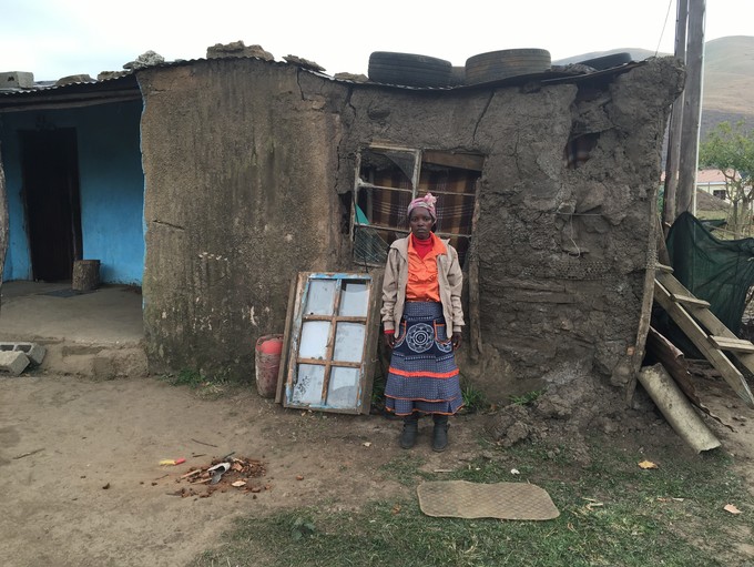 Photo of a woman in front of a mud house