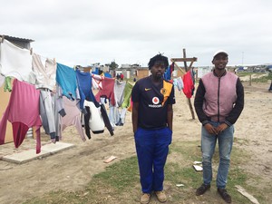 Photo of two men near a shack with washing on a line