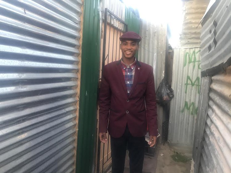 Photo of boy in between shacks