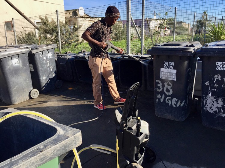Photo of a man hosing down bins