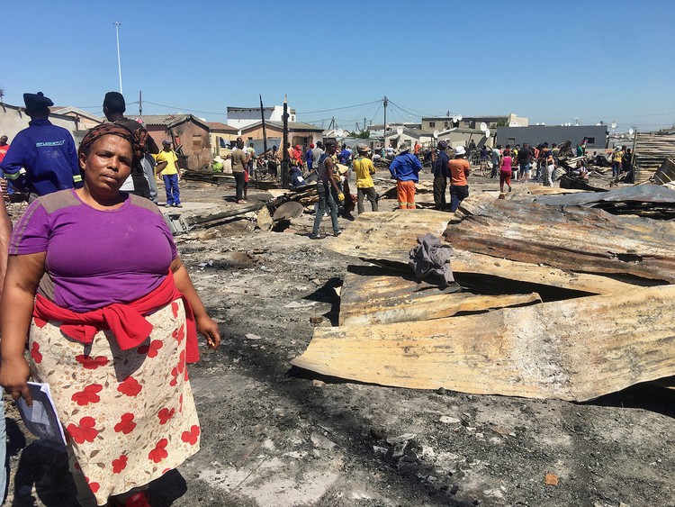 Photo of a woman in front of fire debris