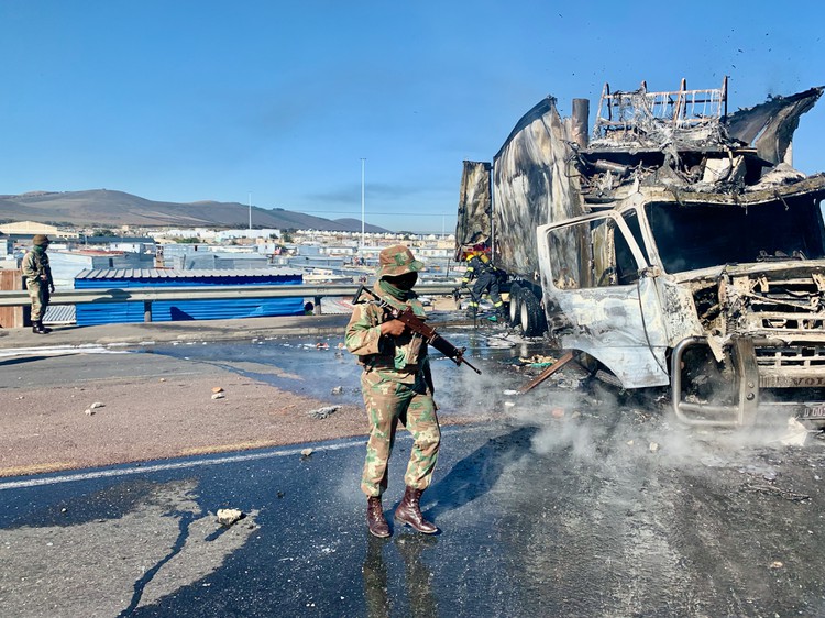 Photo of burnt out vehicle and soldiers