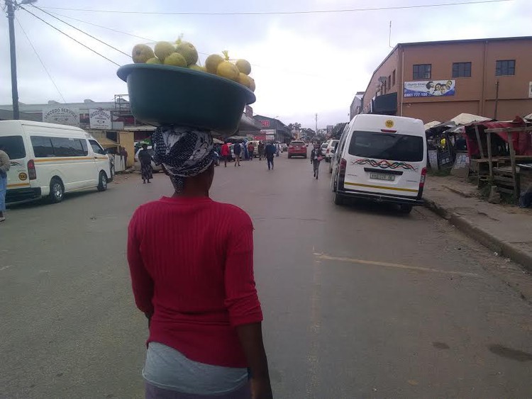 Photo of woman with bucket of oranges on her head