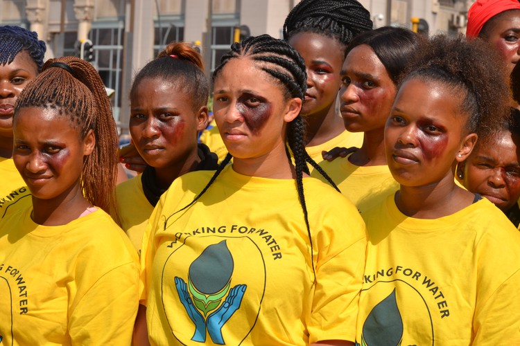 Photo of women in yellow with bruises painted on their faces