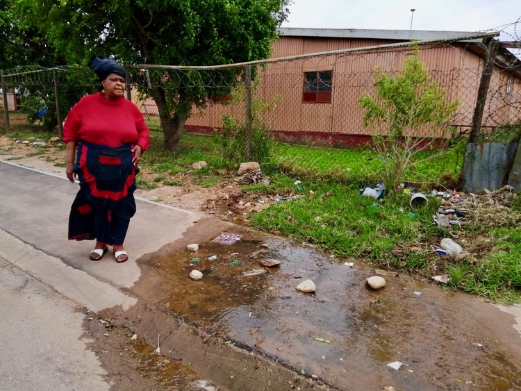 Photo of a woman and water running down a street