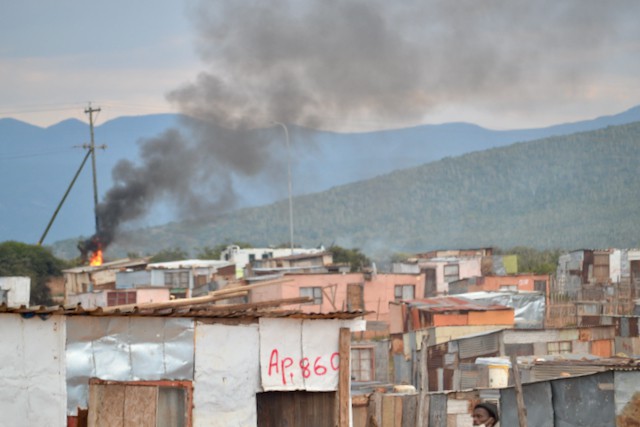 Photo of shacks and a burning electricity pole