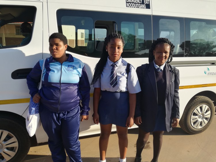 Photo of three learners and a bus
