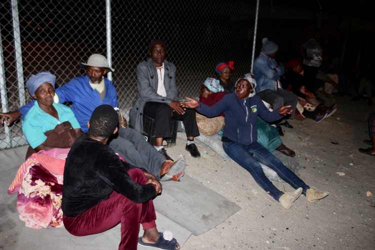 Photo of people sitting on a pavement at night