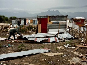 Photo of a demolished shack and a woman