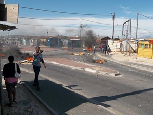 Photo of man gesticulating against backdrop of burning barricade