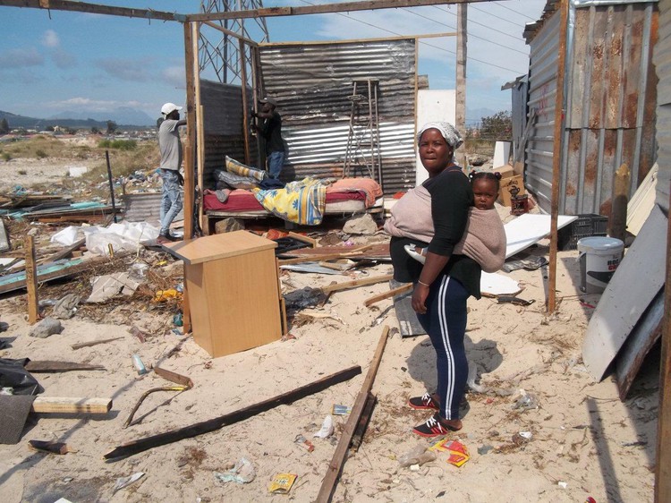 Women standing in front of destroyed shack
