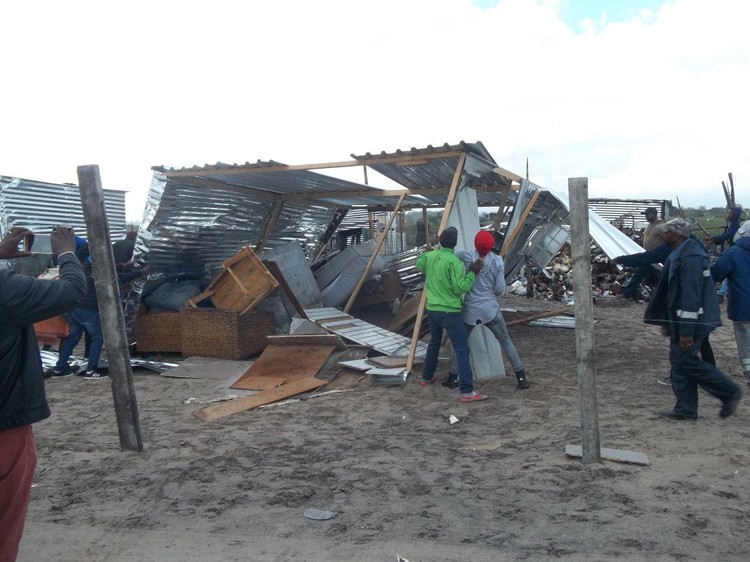 Photo of people next to destroyed shack