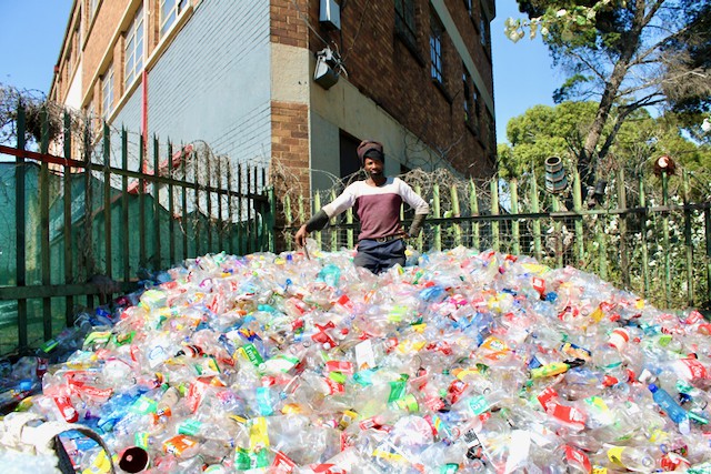 Photo of a man with a huge pile of plastic bottles