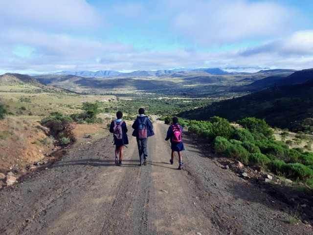 Photo of three learners walking on a rural road