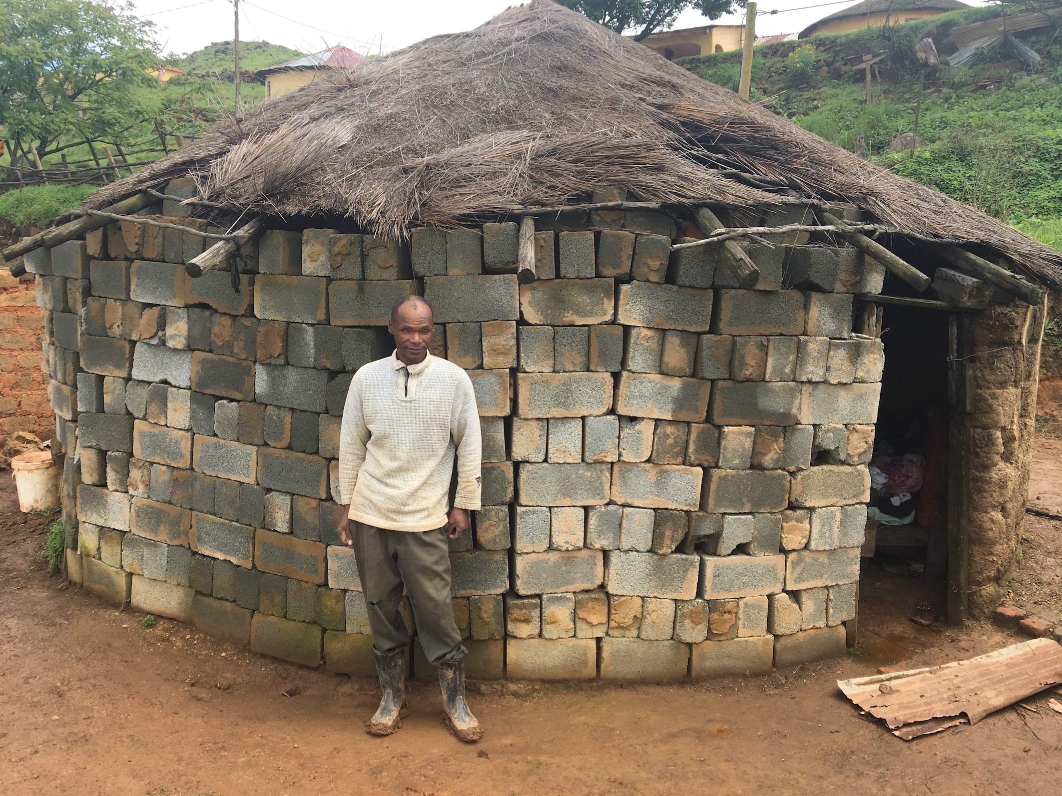 Photo of a man infront of a dilapidated hut